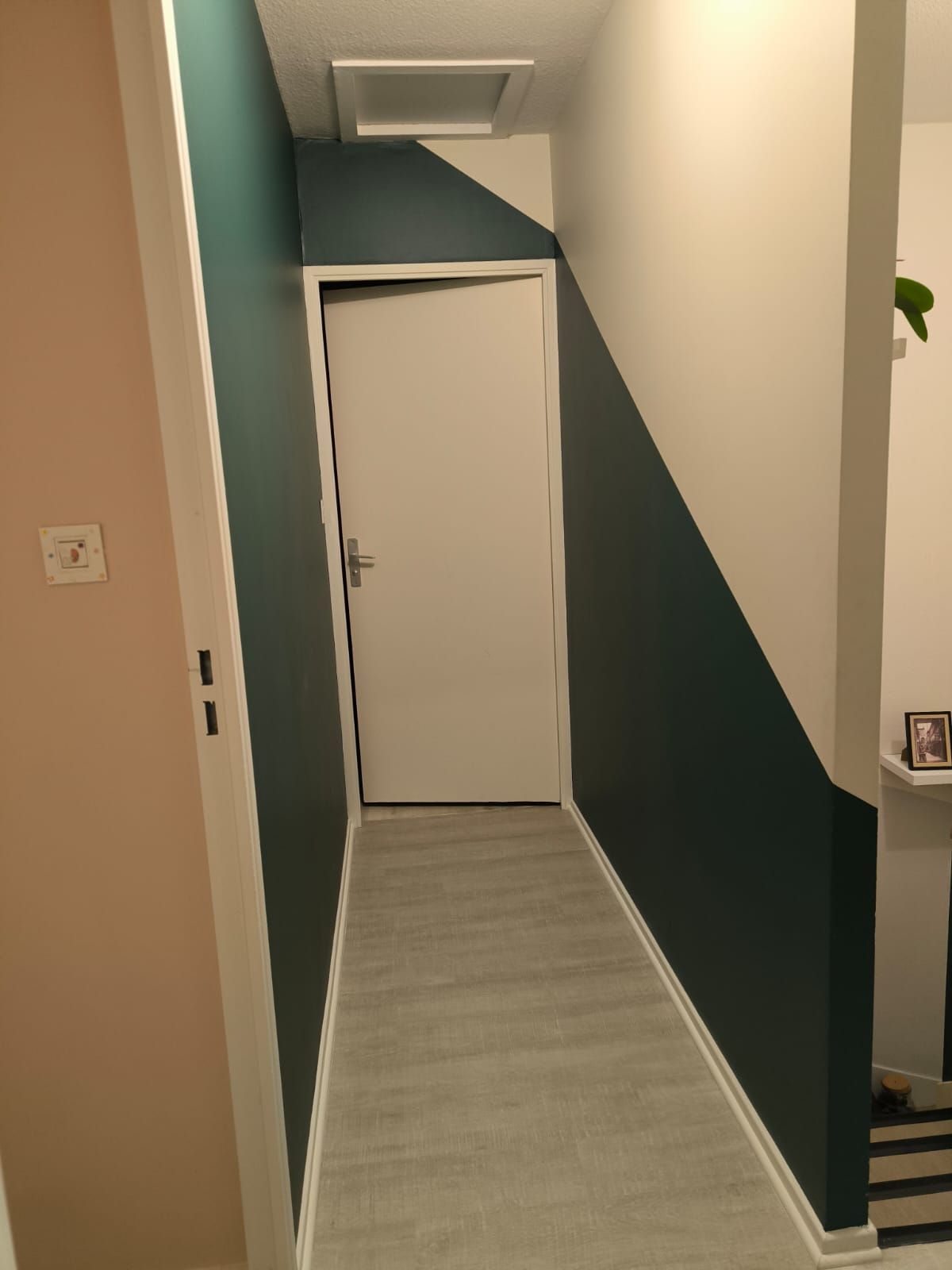 Couloir avec un aplat vert profond peint en diagonale sur les murs