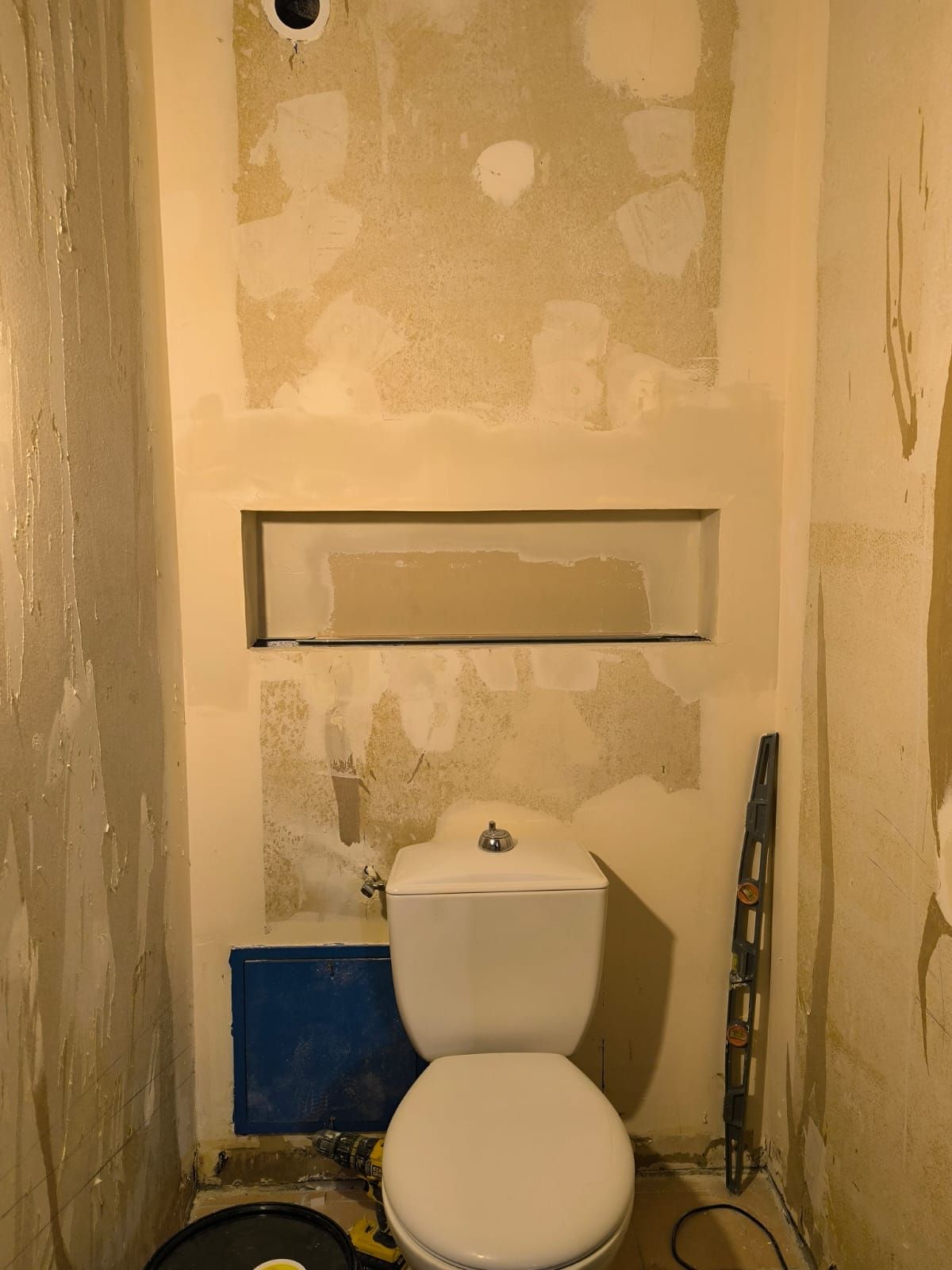 Avant travaux : toilettes aux murs décapés, enduits par endroits