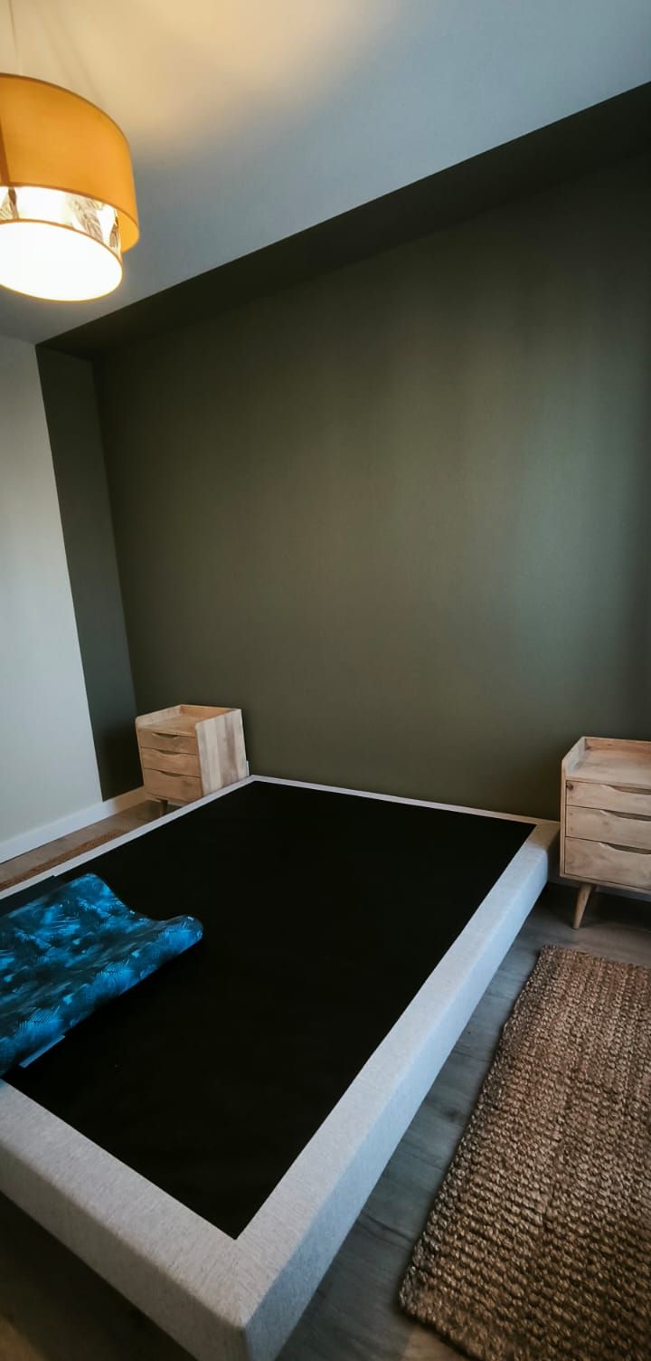 Chambre avec un mur vert profond en tête de lit