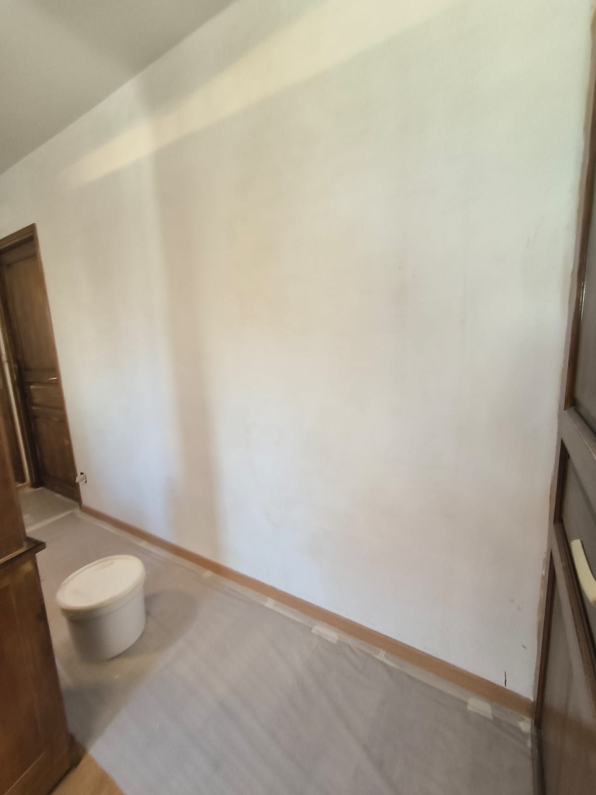 Chantier en cours : mur préparé et sol protégé avant la mise en peinture